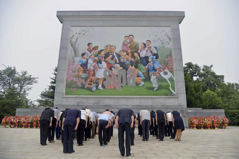 People bow at a mural depicting North Korea's former leaders -- founder Kim Il Sung and his son Kim Jong Il -- in Pyongyang on Sept. 9, 2025, the 77th anniversary of the country's founding. (Photo by Kyodo News/Sipa USA)
