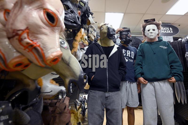 High school students pose for a photo wearing halloween masks at a Spirit Halloween retail store in the Queens borough of New York CityNY, October 21, 2025. It's estimated that Americans will spend more than $13B on Halloween costumes, candy and decorations.  (Photo by Anthony Behar/Sipa USA)