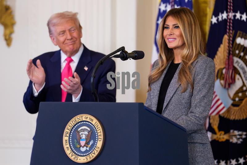 US President Donald Trump, left, looks on as first lady Melania Trump gives remarks in the East Room of the White House during an Executive Order singing event on Thursday, November 13, 2025. President Trump is signing an order that the White House says will boost resources for the foster care system. (Photo by Aaron Schwartz/Sipa USA)