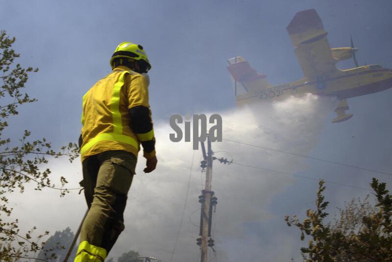 Firefighters and a water bomber are working to extinguish the wildfire in Untes, on 13 July 2026, in Untes, Ourense, Galicia (Spain). A forest fire that broke out in Untes has necessitated the deployment of fire-fighting resources on the ground and in the air, and the temporary closure of the N-120 to facilitate the work of the emergency services. A thick plume of smoke could be seen from the city of Ourense. Photo by Rosa Veiga/Europa Press/Abaca/Sipa USA