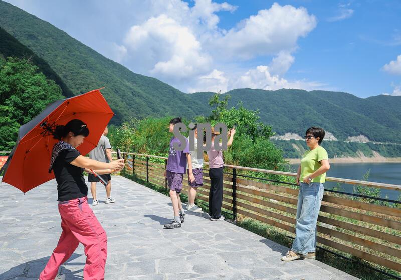 (260820) -- BAISHAN, Aug. 20, 2026 (Xinhua) -- Visitors pose for photos at a sightseeing platform along the Baishan section of national highway G331 in northeast China's Jilin Province, Aug. 19, 2026. Thanks to national highway G331 which opened for public transportation in September 2025, Sandaogou Town, once a remote mountainous town backward in development, has seized new opportunities to foster local businesses in cultivation, tourism and other services. (Xinhua/Xu Chang) (Photo by Xinhua/Sipa USA)