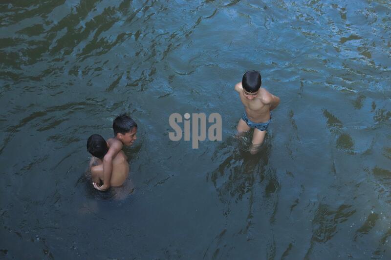 Kashmiri boys cool off in stream in Baramulla