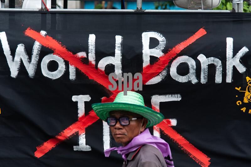 A protester walking past a banner during the demonstration.
Protesters and activists from the Assembly of the Poor and La Via Campesina marched from Lumpini Park to Asoke Intersection to protest against the annual meeting of the International Monetary Fund (IMF) and the World Bank Group in Bangkok. The protesters demanded debt relief for poor nations and an end to financial support for multinational companies. (Photo by Peerapon Boonyakiat / SOPA Images/Sipa USA)